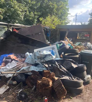 Afvalopslag met autobanden, houtblokken en grofvuil bij woningontruiming