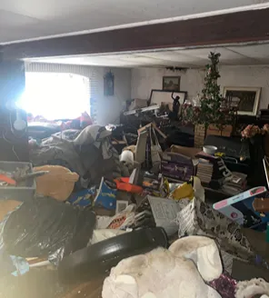 Zwaar vervuilde woonkamer met stapels grofvuil, speelgoed en huisraad