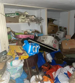 Volgestapelde opslagruimte met vuilnis en huisraad bij complexe terreinontruiming