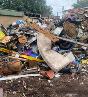 Verwaarloosd erf met puin en afval bij gemeentelijk ontruimd terrein