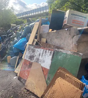 Een vloer waar een brand heeft gewoed, met verbrand puin, roet, gesmolten materialen en metaalconstructies zichtbaar.