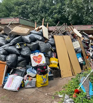 Een enorme hoeveelheid huisraad, vuilniszakken en grofvuil opgestapeld voor een vervallen gebouw.