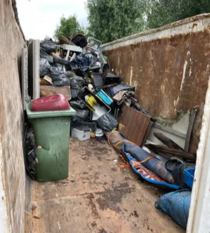 Grote stapel vuilniszakken met daartussen los afval, houten planken en plastic tassen.