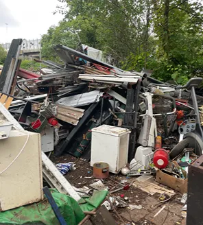 Zelfde terrein als foto 36, met zicht op een enorme hoeveelheid rommel, waaronder meubels, matrassen en huisraad.