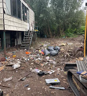 Een vrijgemaakt bospad met links oude barakken en in de verte bouwmaterieel. De grond is bewerkt met rupssporen van graafmachines.