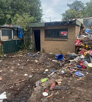 Verwaarloosde tuin met los afval en puin bij ontruimde woning