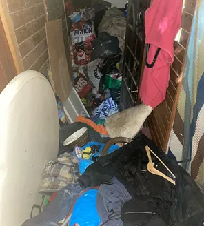 Smalle gang vol afvalzakken en huisraad in zwaar vervuilde woning