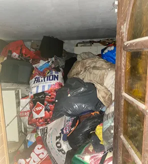 Tot aan plafond gevulde ruimte met vuilniszakken en rommel bij woningontruiming