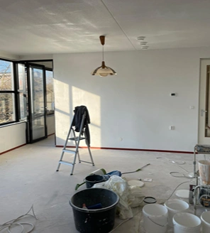 Van-gedateerde-woning-naar-instapklaar-appartement (4) Woonkamer tijdens renovatie met schildermaterialen en ladder aanwezig