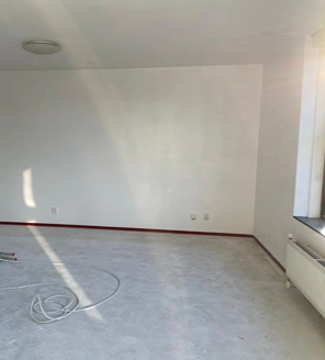 Van-gedateerde-woning-naar-instapklaar-appartement (5) Opgeknapte woonkamer met frisse witte muren en zonlichtinval