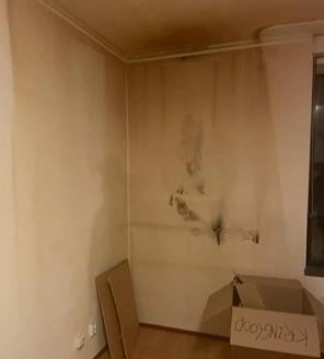 Van-gedateerde-woning-naar-instapklaar-appartement (6) Ernstig vervuilde slaapkamerhoek met zichtbare schade door rookaanslag