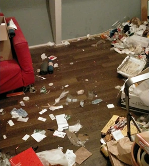 Vloer bezaaid met afval, papieren en verpakkingen naast een rode stoel.