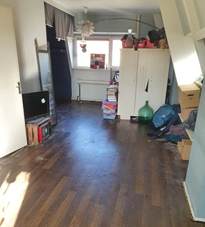 Opgeluchte ruimte na opruiming, met lege vloer en georganiseerde spullen.