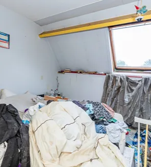 complete-transformatie-van-zwaar-vervuilde-woning-gallerij (20) Slaapkamer vol kleding, dekens en afval voor woningontruiming
