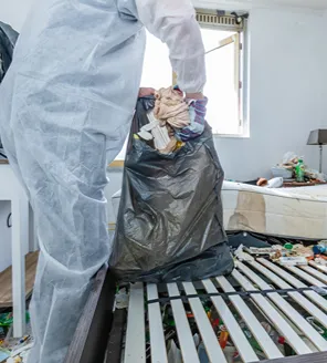 complete-transformatie-van-zwaar-vervuilde-woning-gallerij (5) Schoonmaker in beschermende kleding verwijdert afval tijdens diepe schoonmaak