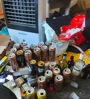 een-huis-opgeruimd-voor-een-frisse-start (6) Hoek van een kamer met tientallen energiedrankblikken en lege flessen op de grond.