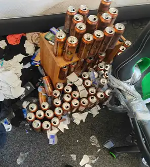 een-huis-opgeruimd-voor-een-frisse-start (7) Kamer met enorme hoeveelheid lege verpakkingen en drankblikken verspreid over de vloer.