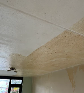 nicotine-verwijderen-en-woning-ontruimen (1) Aangetast plafond met gele nicotineaanslag in een woning vóór reiniging.