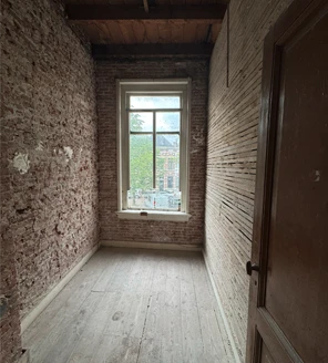 pand-ontruimen-kamer-renovatieklaar Het resultaat van een pand ontruimen: een schone kamer met blootgelegde bakstenen muren, klaar voor renovatie of inrichting.