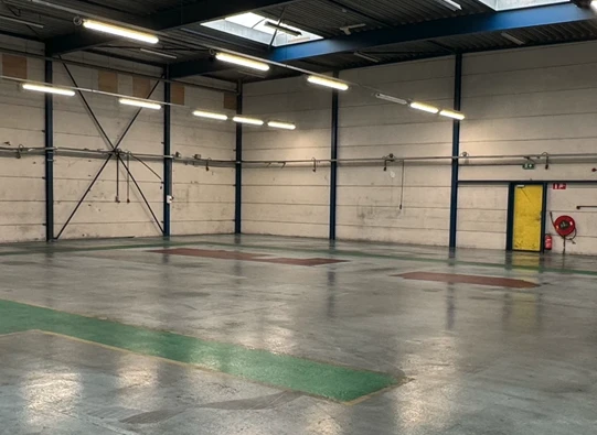 Een lege en schone bedrijfshal met glanzende betonvloer na oplevering van industriële schoonmaak in regio Rijswijk.