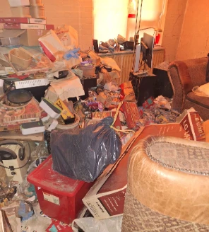 Woonruimte volledig gevuld met afval, dozen, papier en meubels vóór ontruiming