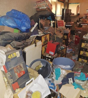 Kamer met stapels dozen, rekken en verspreide spullen in verzamelwoning