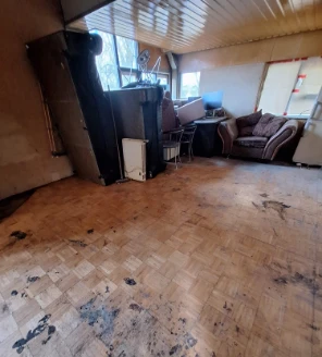 Woonruimte na ontruiming met achtergebleven vuil op houten vloer