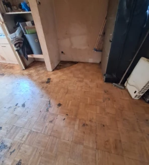 Vervuilde houten vloer in leeggeruimde woonruimte na woningontruiming