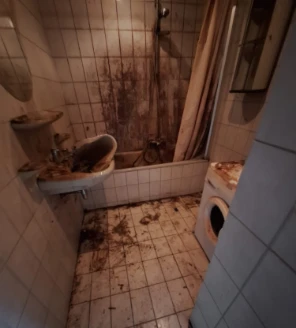 Vervuilde badkamer na ontruiming met aangetaste tegels, wastafel en bad