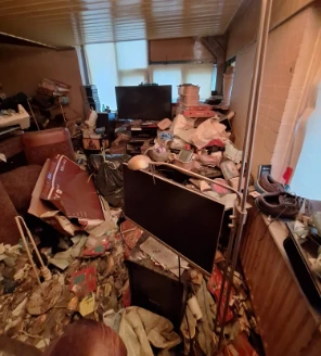 Tot het plafond gevulde woonruimte met papier, afval en apparatuur bij verzamelwoning