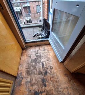 Leeggeruimde doorgang naar balkon met zichtbaar vervuilde vloer