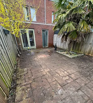 project-overwoekerde-tuin-gallerij (3) Opgeknapte tuin met schone tegels en zicht op de achterzijde van de woning