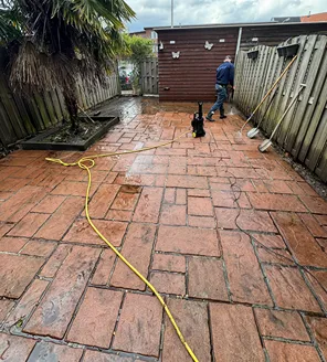 project-overwoekerde-tuin-gallerij (6) Tuinreiniging in volle gang met hogedrukreiniger en bezems langs de schutting