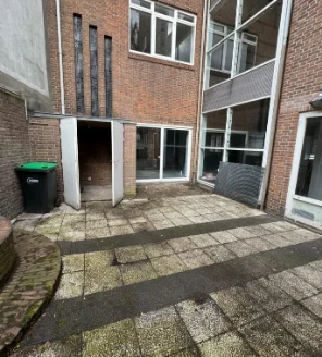 Opgeruimde achtertuin met gereinigde tegels en open doorgang