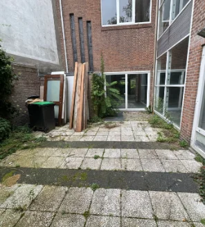 Tuin met losse materialen en vuil op tegels vóór schoonmaak