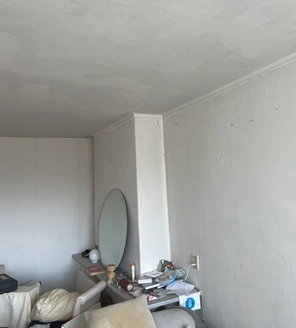 van-ontruiming-tot-verkoopklaar-maken (2) Rommelige hoek van een woonkamer met spiegel, kaarsen en diverse spullen op de vensterbank.