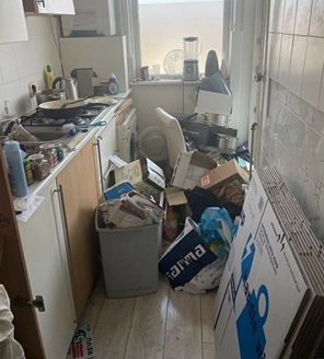 van-ontruiming-tot-verkoopklaar-maken (3) Sterk vervuilde keuken met vuilnis, dozen en een overvolle prullenbak.