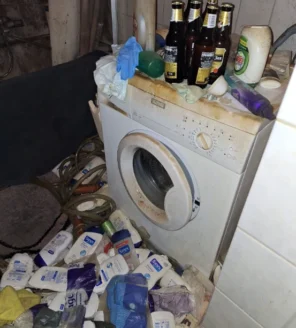 Wasmachine in zwaar vervuilde ruimte vóór woningontruiming