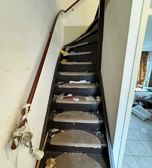 Zolderkamer met opgestapelde dozen en losse voorwerpen voor ontruiming