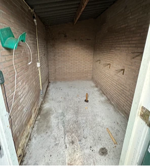 Leeggeruimde schuur met betonnen vloer na ontruiming van opslagruimte