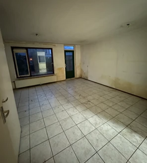 Woonkamer met witte tegels, volledig ontruimd en klaar voor renovatie