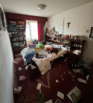 Woonkamer met stapels vuilniszakken, meubels en achterstallige schoonmaak