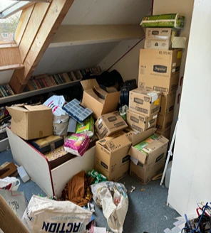 Woonkamer bezaaid met papierafval en restanten inboedel vóór ontruiming