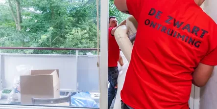 Medewerker van Ontruiming de Zwart draagt een doos bij het leeghalen van een woning